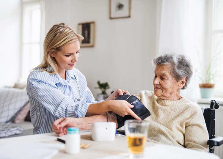 Frau mißt Blutdruck bei älterer Frau