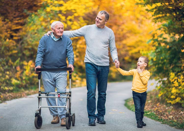 Älterer Mann mit Rollator geht mit Sohn und Enkel spazieren