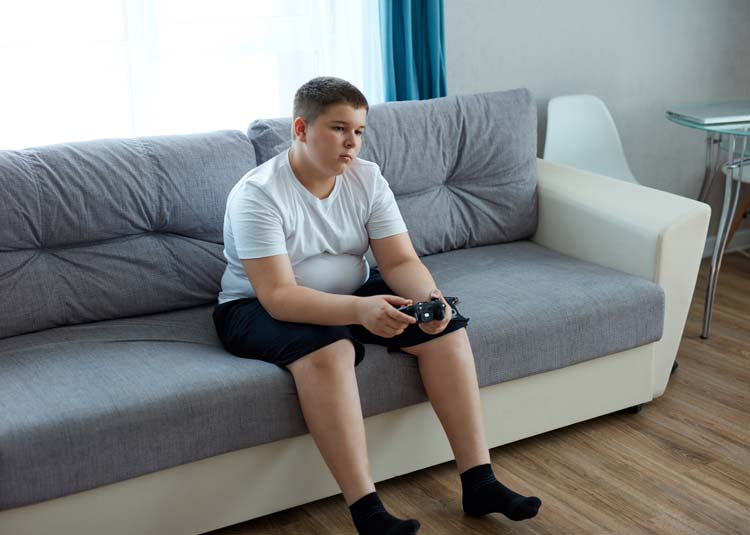 Junge sitzt auf Couch und spielt Computer