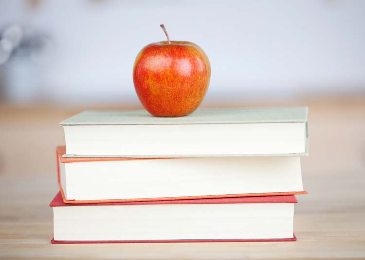Apfel liegt auf einem Bücherstapel
