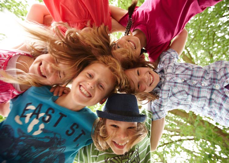 Sechs fr&ouml;hliche Kinder stecken ihre K&ouml;pfe in einem Kreis zusammen