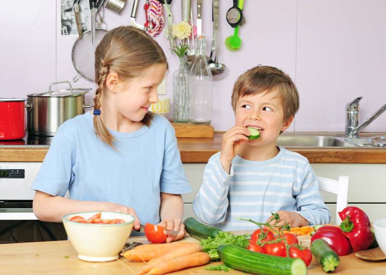 Mädchen und Junge bereiten Gemüse zu
