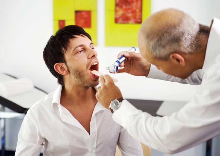 Arzt untersucht Rachen eines Patienten