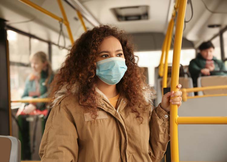 Frau mit einer Gesichtsmaske fährt Bus