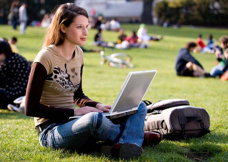 Junge Frau sitzt mit Notebook im Park