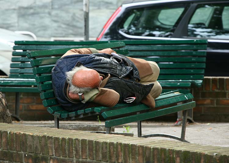 Obdachloser Mann liegt auf Bank