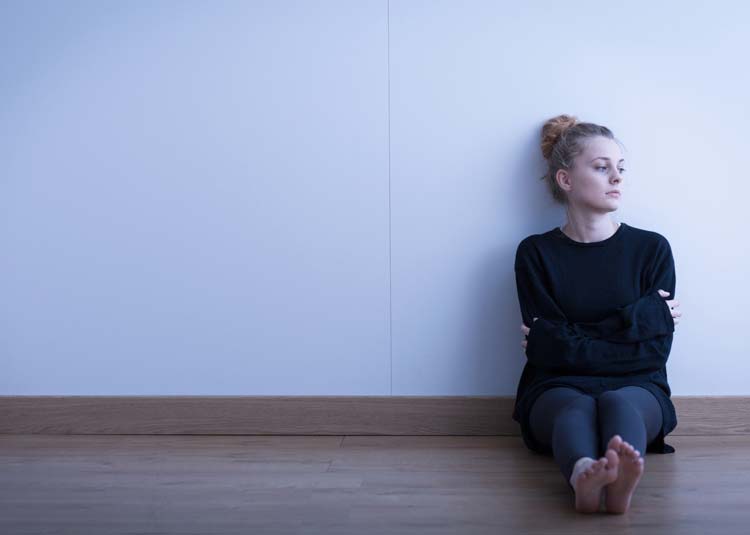 Traurige junge Frau sitzt auf Boden