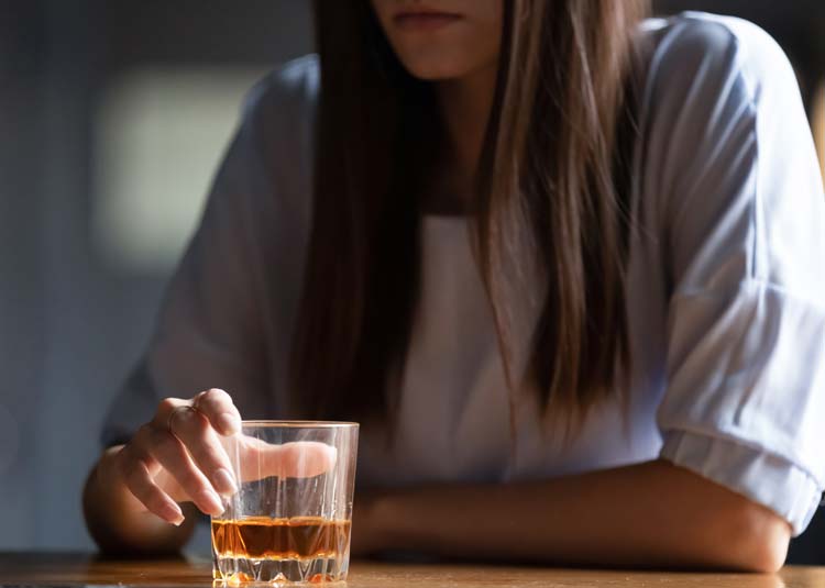 Frau hat ein Glas mit hochprozentigem Alkohol vor sich stehen