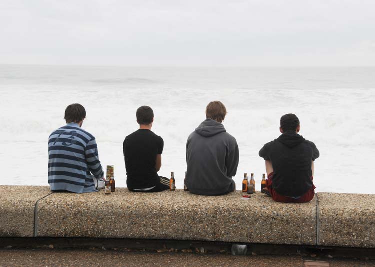Jugendliche sitzen mit Bierflaschen draußen